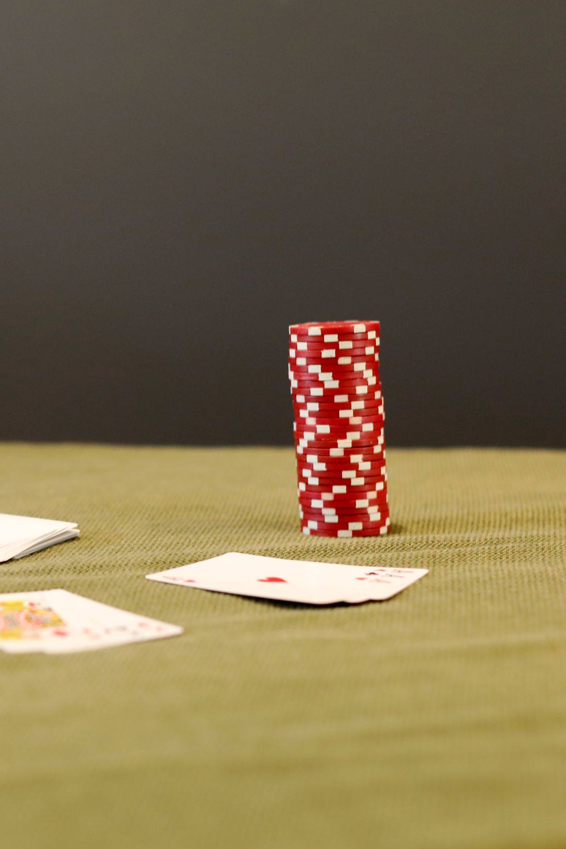 Chip poker merah tersusun di atas meja felt hijau